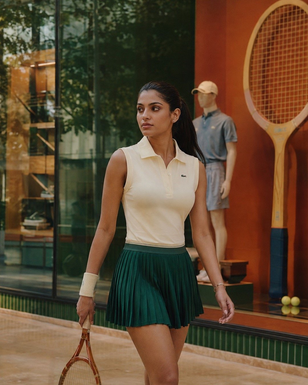 An Indian fashion model in cream and green on a terracotta tennis court